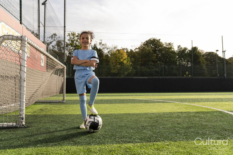 Portrait of girl with ball next to soccer goal