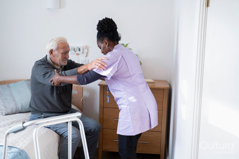 Caregiver helping senior man to get up from bed