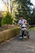 Nurse and senior woman in wheelchair going on walk in park