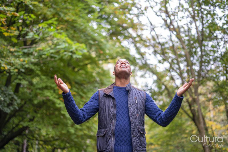 Smiling man standing in forest and looking up