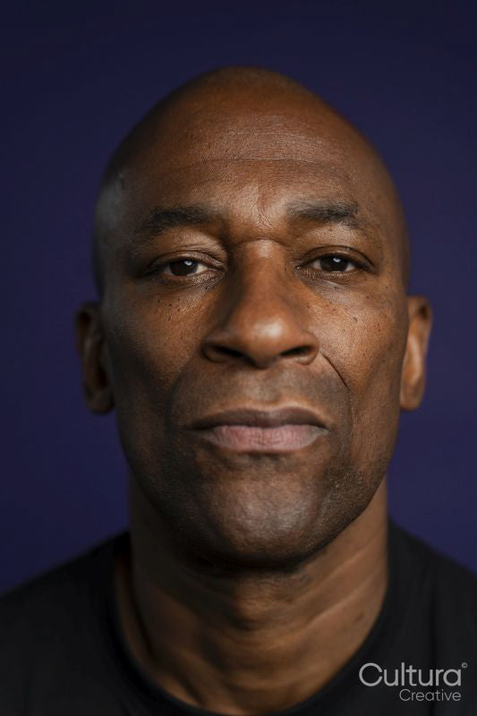 Portrait of serious man looking at camera against purple background