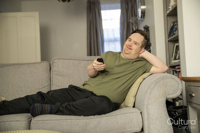 Man sitting on sofa and using remote control