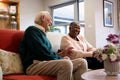 Smiling senior man and woman sitting on sofa in nursing home