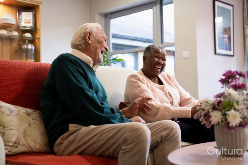 Smiling senior man and woman sitting on sofa in nursing home