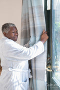Smiling senior woman in bathrobe standing by window