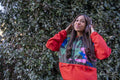 South Yorkshire, Smiling woman with headphones in front of leafy bush