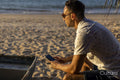 Man sitting at beach and using smart phone