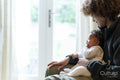 Baby girl sitting on mother's lap at home