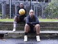 Portrait of female friends sitting outdoors with basketball