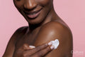 Young woman applying cream on shoulder