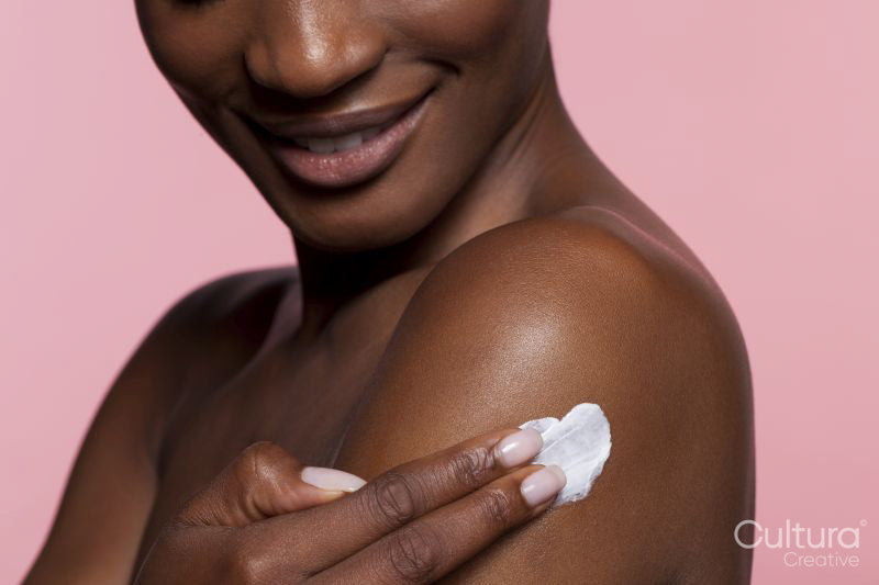 Young woman applying cream on shoulder