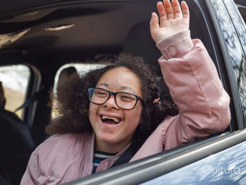 Girl waving out of car window