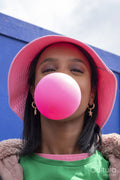 Portrait of young woman in bucket hat blowing bubble gum