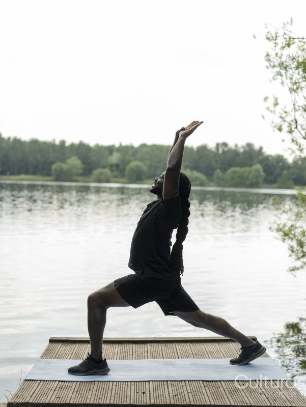 Man practicing yoga by lake