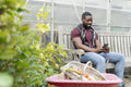 Man with smart phone sitting on bench in allotment