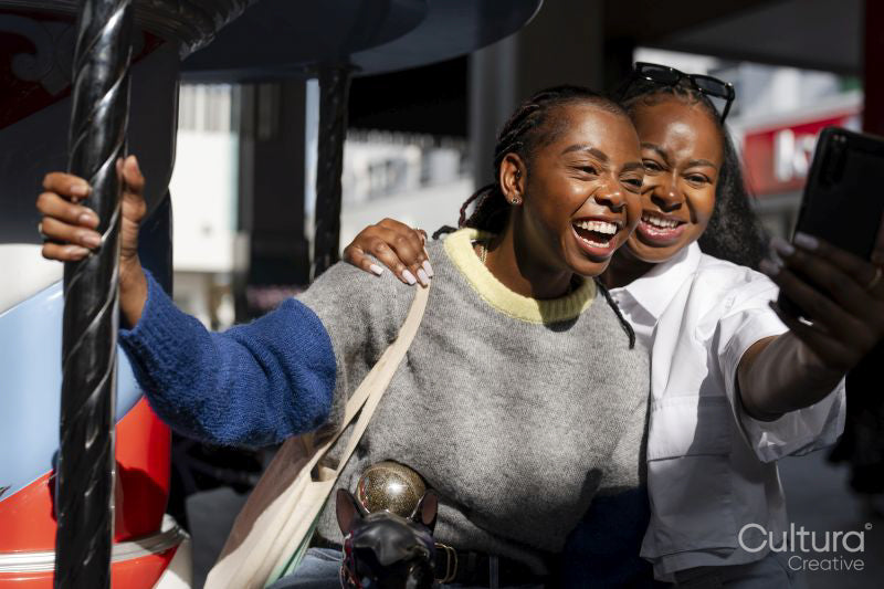 Young female friends taking selfie on merry-go-round
