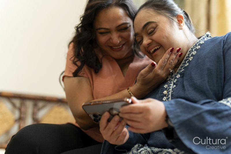 Woman with down syndrome daughter using smart phone at home