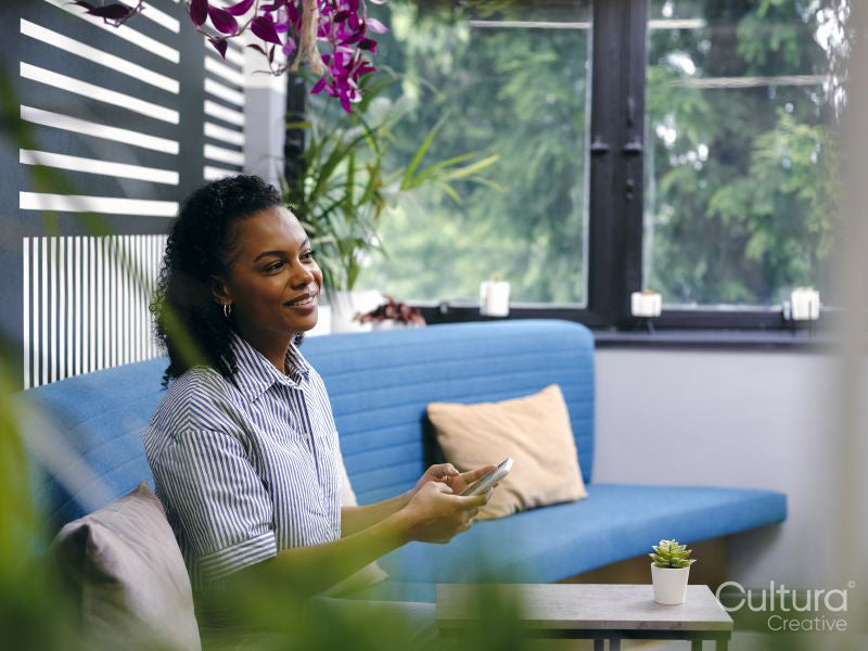 Woman sitting on sofa using smart phone