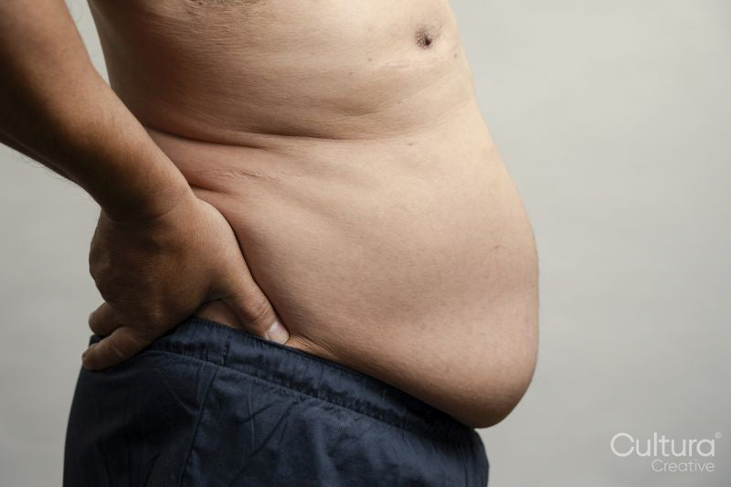 Profile view of man with pot belly against gray background