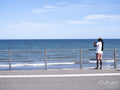 Man standing on promenade and photographing sea