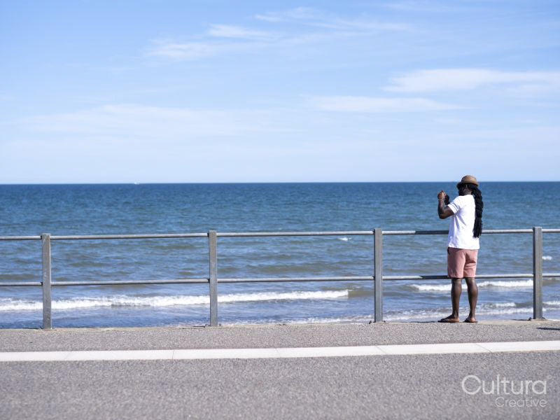 Man standing on promenade and photographing sea