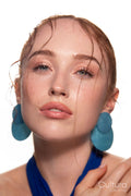 Studio portrait of a woman in a blue dress and large blue earrings