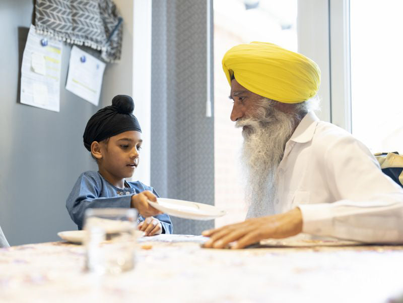 Grandfather and grandson in traditional clothing setting table