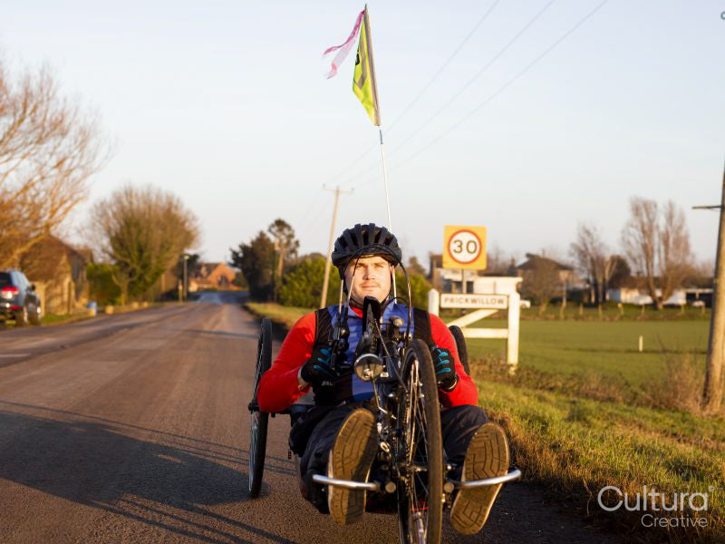 Disabled man riding handcycle on country road