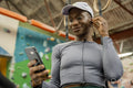 Woman with in-ear headphones and smart phone at gym
